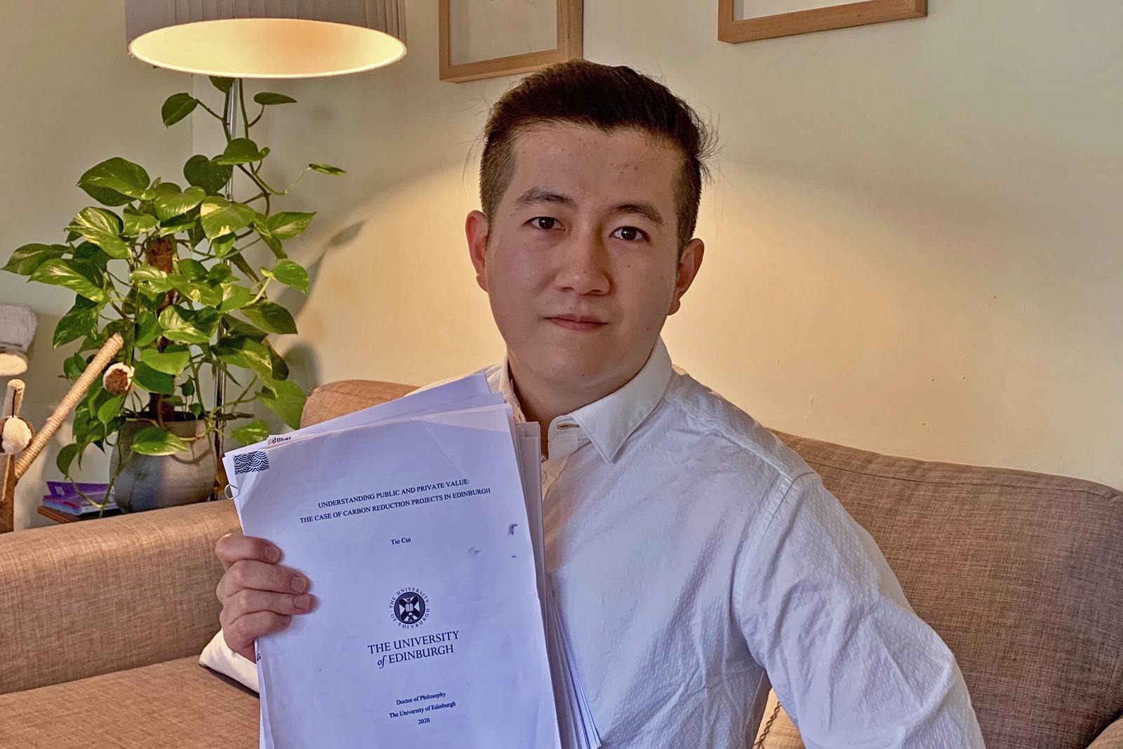 Tie Cui holding his PhD thesis paper